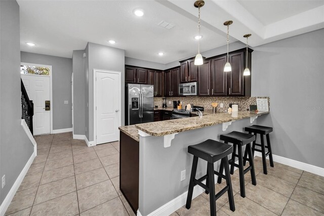 kitchen with pendant lighting, backsplash, light stone counters, kitchen peninsula, and stainless steel appliances