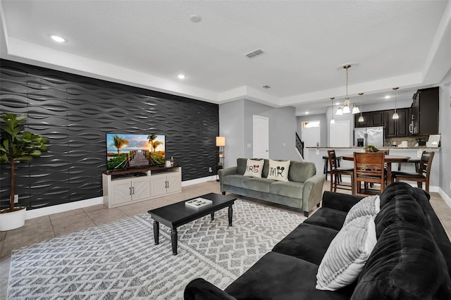 tiled living room with a raised ceiling and a notable chandelier