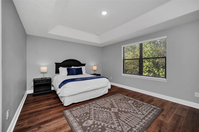 bedroom featuring dark hardwood / wood-style floors and a raised ceiling