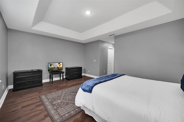 bedroom with a raised ceiling and dark wood-type flooring