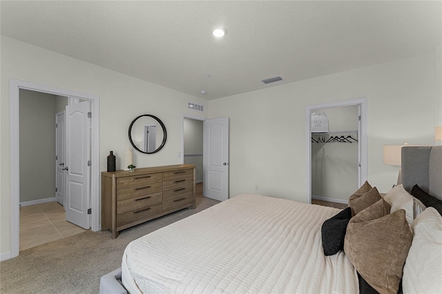 carpeted bedroom featuring a walk in closet and a closet