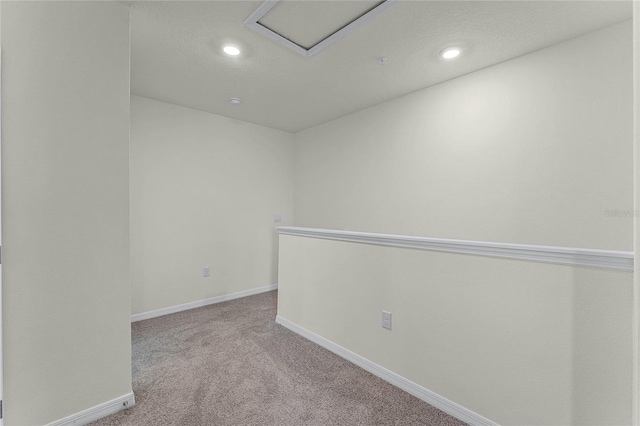 empty room with light colored carpet and a textured ceiling