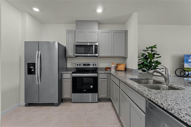 kitchen with light stone countertops, appliances with stainless steel finishes, sink, gray cabinets, and light tile patterned flooring