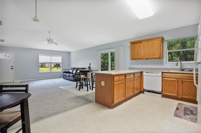 kitchen featuring a wealth of natural light, dishwasher, decorative light fixtures, and sink