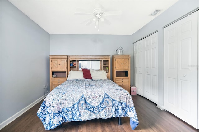 bedroom with two closets, ceiling fan, and dark wood-type flooring