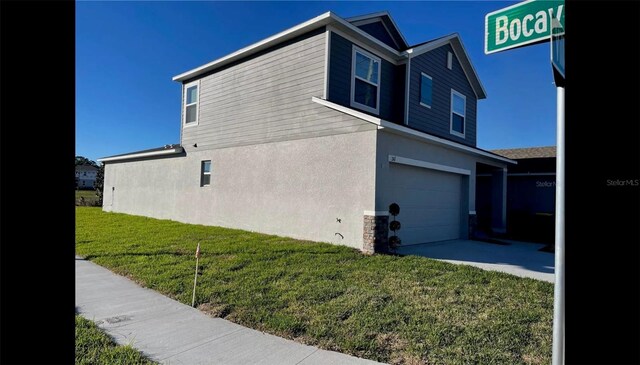 view of side of property featuring a garage and a lawn