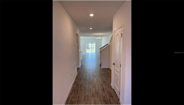 hall featuring dark wood-type flooring and a notable chandelier