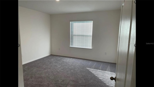 unfurnished room featuring dark colored carpet