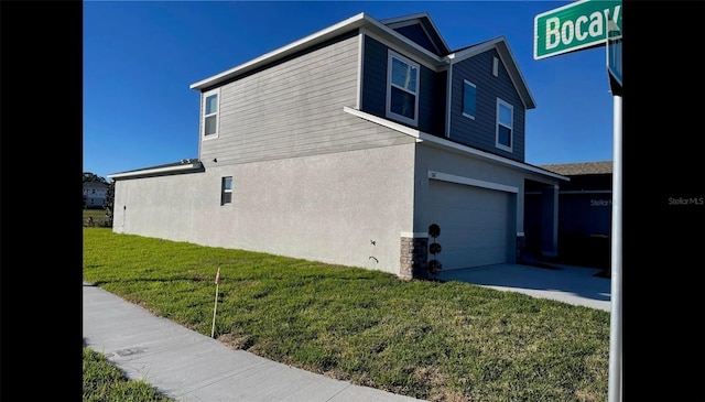view of side of property with stucco siding, concrete driveway, a lawn, and a garage