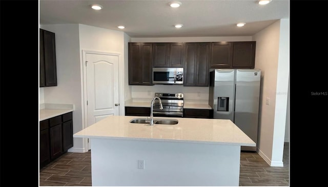 kitchen with a sink, wood tiled floor, baseboards, appliances with stainless steel finishes, and recessed lighting