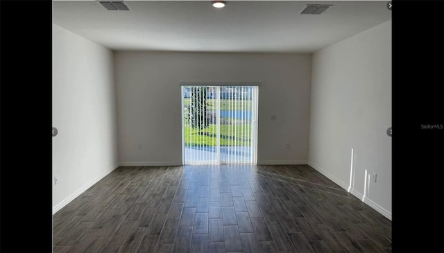empty room featuring baseboards, dark wood-style flooring, and visible vents