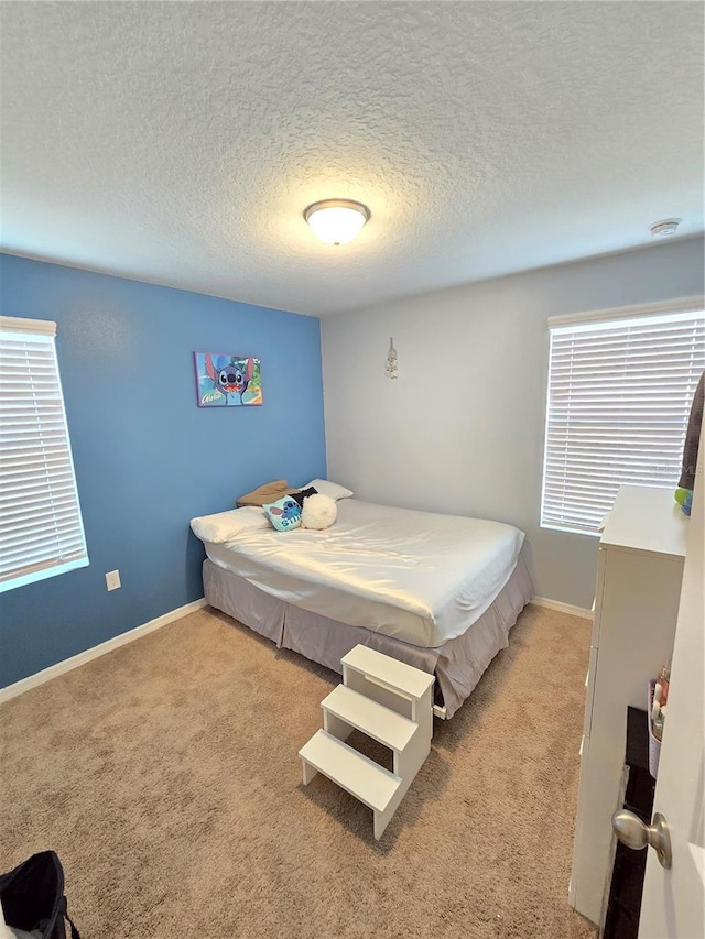 carpeted bedroom with a textured ceiling and multiple windows