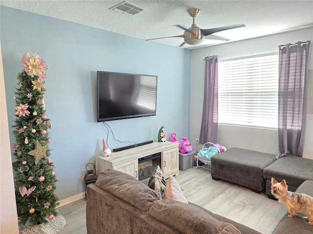 living room featuring ceiling fan, a textured ceiling, and light hardwood / wood-style flooring