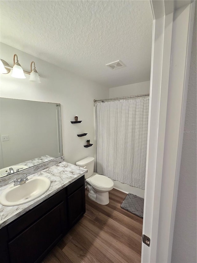 bathroom with hardwood / wood-style floors, vanity, a textured ceiling, and toilet