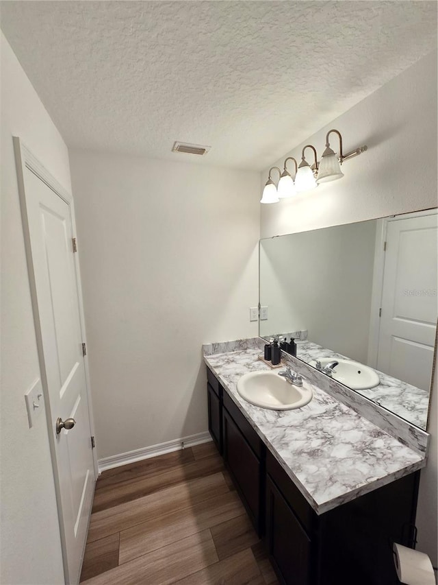 bathroom with vanity, wood-type flooring, and a textured ceiling