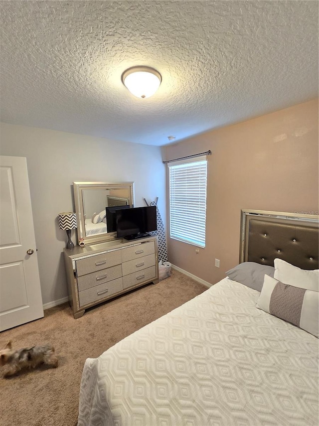 bedroom with light colored carpet and a textured ceiling