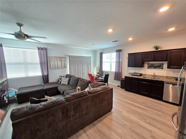 living room featuring a textured ceiling, ceiling fan, light wood-type flooring, and sink