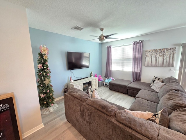 living room with ceiling fan, light hardwood / wood-style flooring, and a textured ceiling