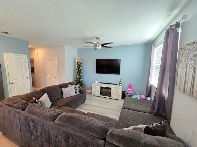 living room featuring a textured ceiling, light hardwood / wood-style floors, and ceiling fan