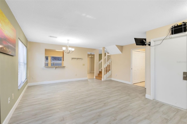 unfurnished living room with a chandelier and light wood-type flooring