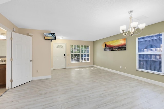 empty room with light hardwood / wood-style flooring, a chandelier, and sink