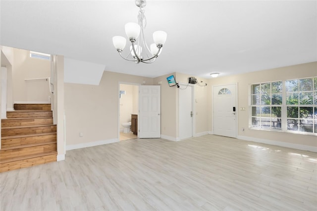 unfurnished living room featuring light wood-type flooring, baseboards, a notable chandelier, and stairway