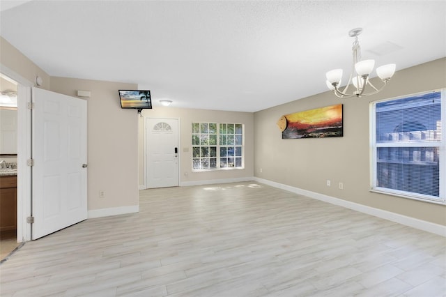 interior space featuring an inviting chandelier, baseboards, and light wood-type flooring