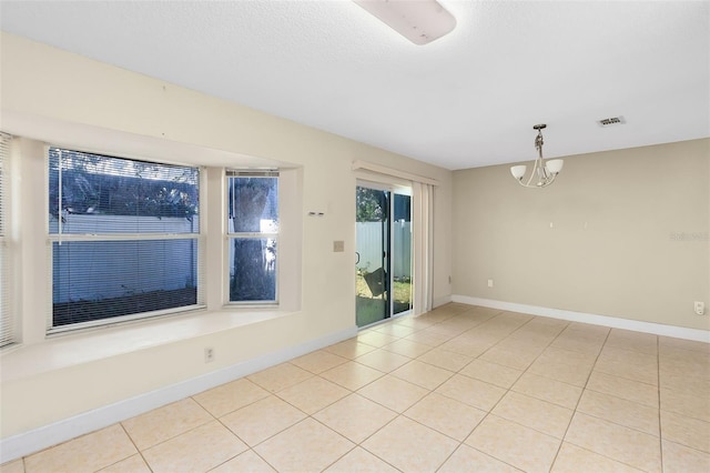spare room with baseboards, visible vents, light tile patterned floors, and an inviting chandelier