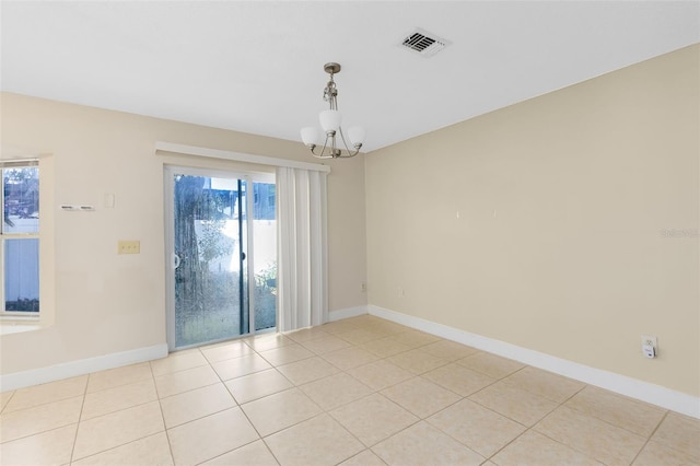 spare room featuring an inviting chandelier, baseboards, and a healthy amount of sunlight