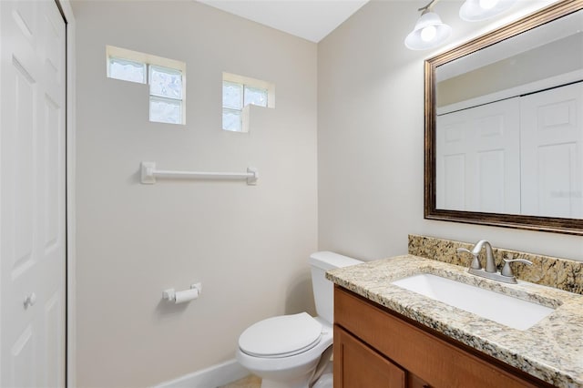 bathroom featuring vanity, baseboards, a closet, and toilet
