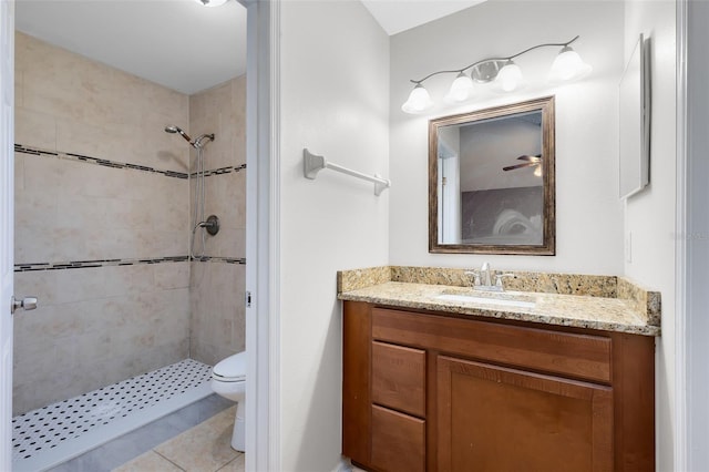 full bathroom featuring toilet, a tile shower, and vanity