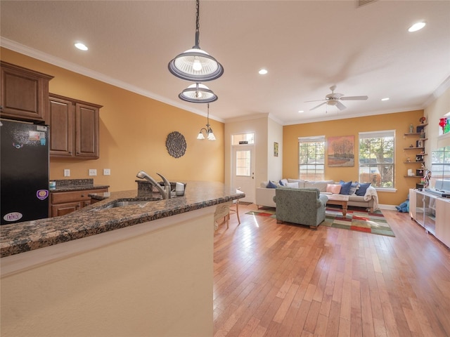 kitchen featuring black refrigerator, crown molding, sink, hanging light fixtures, and light hardwood / wood-style floors