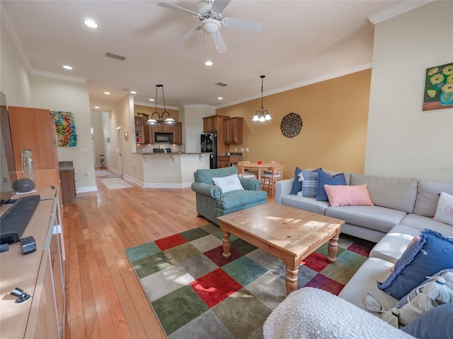 living room with crown molding, ceiling fan with notable chandelier, and light wood-type flooring