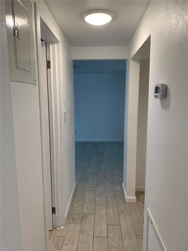 corridor featuring electric panel and light hardwood / wood-style floors