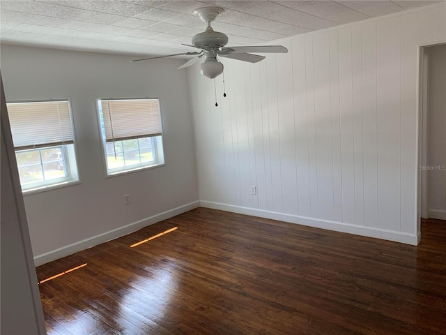 empty room with ceiling fan, wood walls, dark hardwood / wood-style flooring, and lofted ceiling