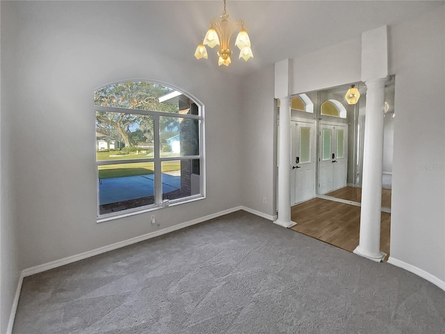 carpeted empty room with a chandelier and decorative columns