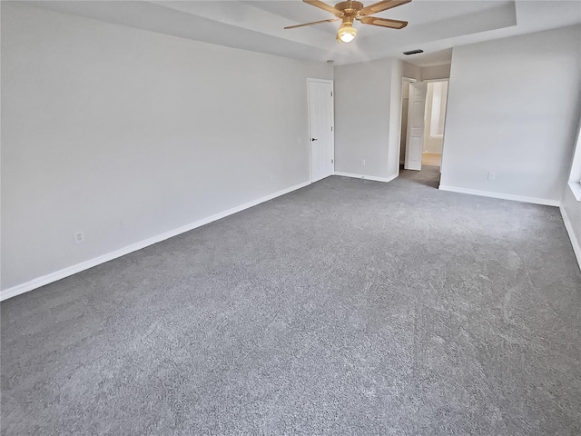 spare room featuring dark colored carpet and ceiling fan