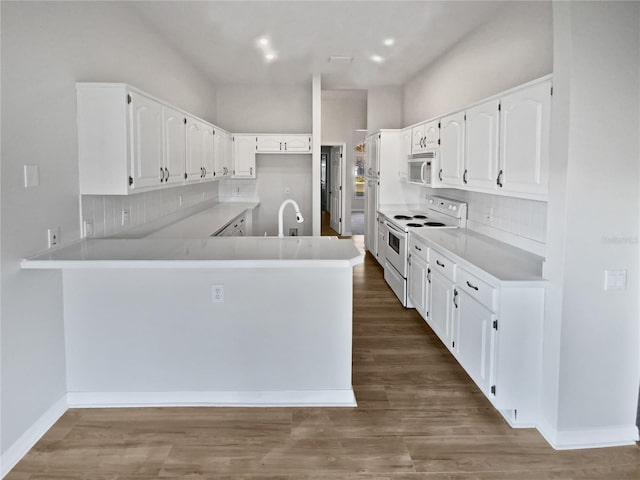 kitchen featuring white cabinets, white appliances, kitchen peninsula, and dark wood-type flooring