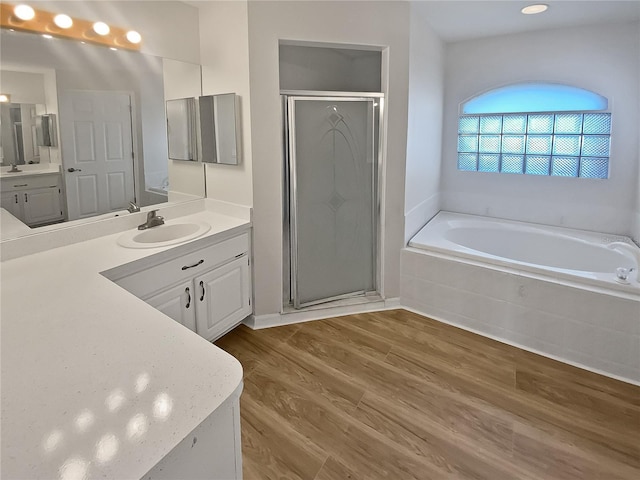 bathroom with hardwood / wood-style floors, vanity, and separate shower and tub