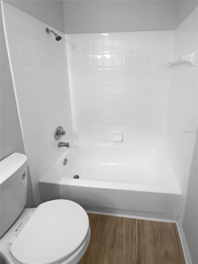 bathroom with hardwood / wood-style flooring, toilet, and tiled shower / bath