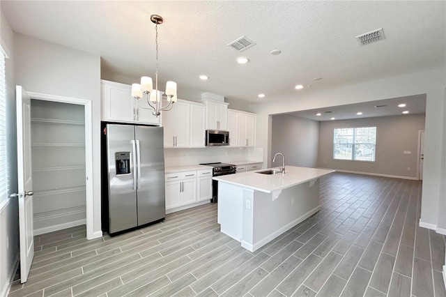 kitchen featuring pendant lighting, sink, appliances with stainless steel finishes, an island with sink, and white cabinets