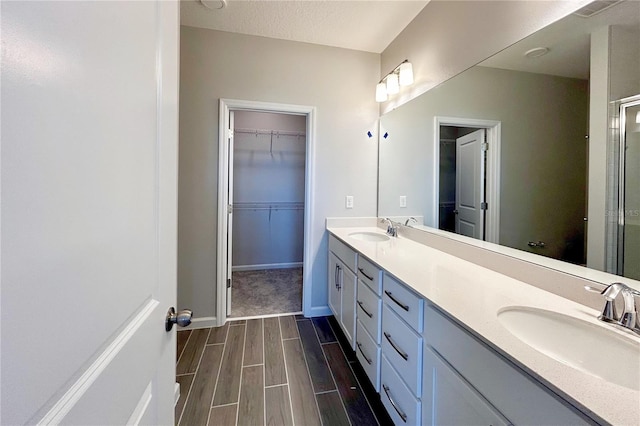 bathroom featuring vanity, an enclosed shower, and a textured ceiling