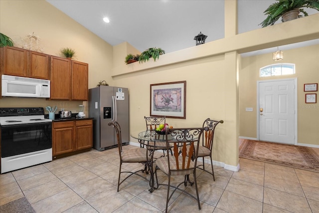 kitchen with light tile patterned floors, high vaulted ceiling, hanging light fixtures, and white appliances