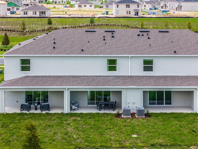 back of house with central air condition unit, a patio area, and a lawn