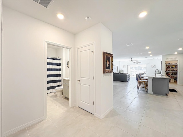 hallway featuring sink and light tile patterned flooring