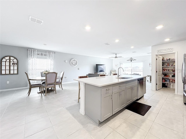 kitchen featuring gray cabinetry, ceiling fan, sink, stainless steel appliances, and an island with sink