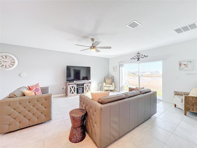 living room featuring ceiling fan, light tile patterned floors, and a textured ceiling