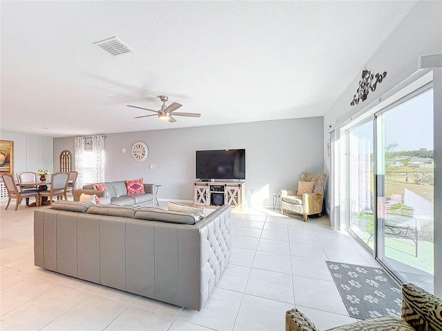 living room featuring a wealth of natural light, light tile patterned floors, and ceiling fan