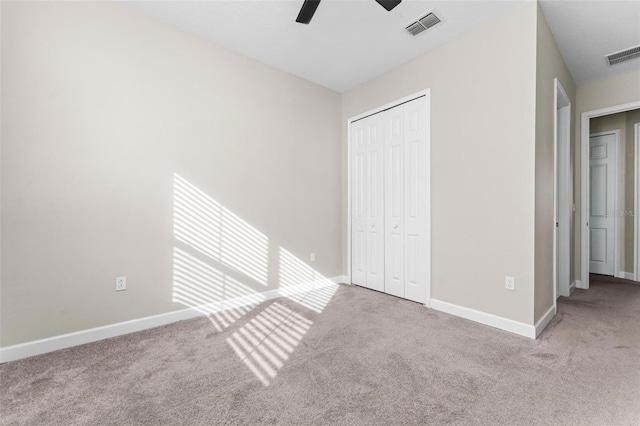 unfurnished bedroom featuring ceiling fan, light colored carpet, and a closet