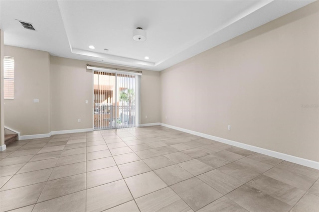 spare room featuring light tile patterned flooring and a tray ceiling